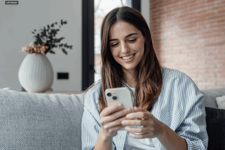 A woman smiling at her phone.